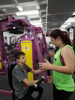 Photo of a coach teaching an athlete to use a chest press weight machine