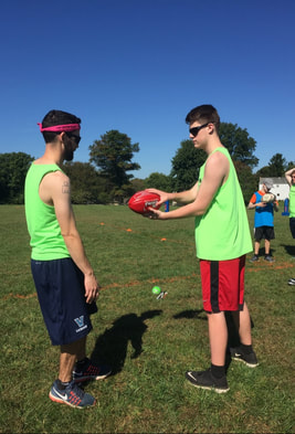 Photo of a coach teaching an athlete to throw a rugby pass