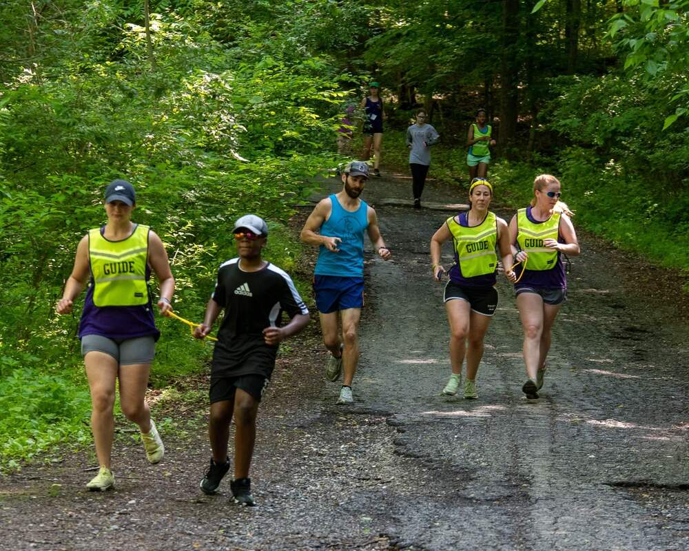 Photo of several coaches and athletes guide running down a hill in the Gordon Natural Area
