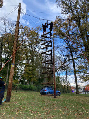 Photo of 2 athletes on top of a high ropes element
