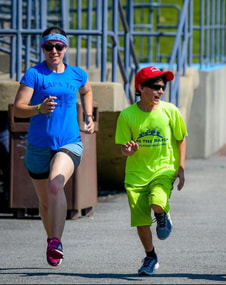 Photo of Coach Maria running with an athlete. 