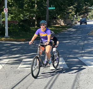 Photo of Maria riding pilot on a tandem bike with an athlete. 